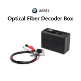 Black optical fiber decoder box with labeled input ports, surrounded by red and white BMW E90-E93 car stereo logic 7 sound system.